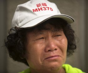 A woman wearing a hat that says "Pray for MH370" cries outside the Ministry of Foreign Affairs in Beijing.