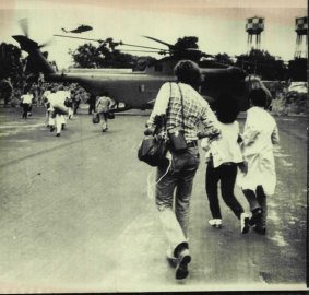 Americans and Vietnamese run for a US Marine helicopter during the evacuation of Saigon Tuesday. April 29, 1975. 