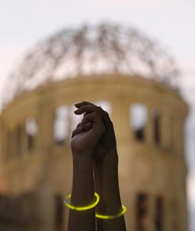 Two women hold hands after forming a human chain to surround the gutted Atomic Bomb Dome in Hiroshima during an event to commemorate victims of the atomic bombing. 