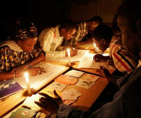 Senegalese election workers count votes by the light of candles and a kerosene lamp at a polling station without electricity.