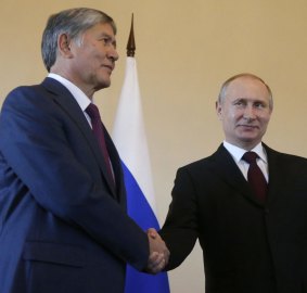 Putin smiles as he shakes hands with Atambayev.