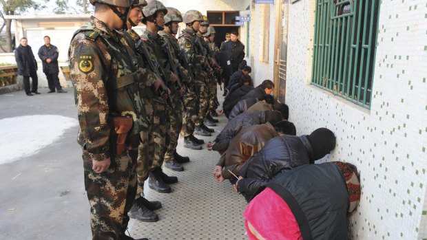 Paramilitary policemen guard suspects during the Boshe village raid.