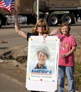 Mourners wave as the hearse carrying Ronald Reagan's casket passes in California in 2004.