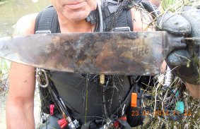 A police diver holds one of the knives recovered from the dam.