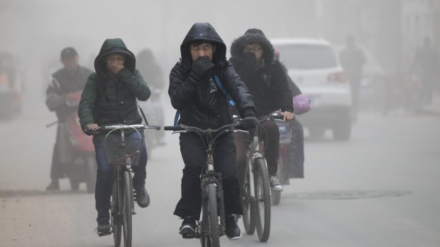 Public concerns: Residents cover their face from dust as they ride their bicycles along a street on a hazy day in Zhengzhou, Henan province.