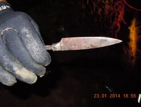 A diver holds a knife found in the dam.