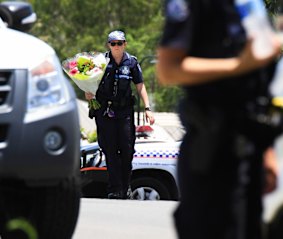 A police officer takes flowers delivered by a neighbour to the scene where Ms Bradford and her estranged husband's bodies were found.