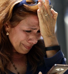 A woman tries to speak on her phone after she evacuated following an earthquake in Mexico City.