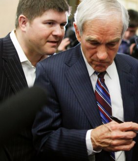 Representative Ron Paul listens as campaign chairman Jesse Benton has a word with him in 2011.