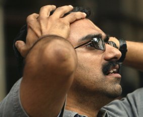 An onlooker reacts as he watches stock prices on a screen on the facade of the Bombay Stock Exchange in Mumbai, India, Monday, Sept. 15, 2008. What we now call the GFC.