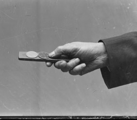 The hand of a spinner holding a two-up kip in Reservoir Street, Sydney, 1930.