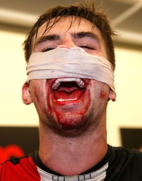 Bruised and bloodied, but happy, Billy Longer of the Saints sings the team song in the rooms.