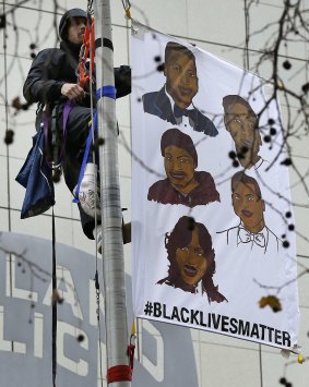 Widely visible: A protester hangs a banner atop the flagpole of the Oakland Police Department.