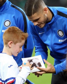Inter's captain Mauro Icardi hands Anne Frank's diary to a child after signing it, prior the Italian Serie A soccer match between Inter and Sampdoria at the San Siro stadium in Milan, Italy.