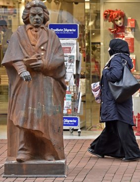 A Muslim woman passes a statue of composer Ludwig van Beethoven in Bonn, Germany.