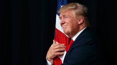 Donald Trump hugs an American flag at a campaign rally in October.