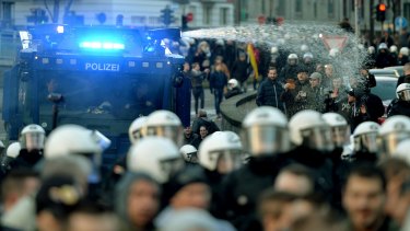 Police drive back right-wing demonstrators using a water cannon during protests in Cologne.