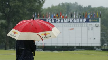 A man stands by the 18th hole after third round play was suspended.