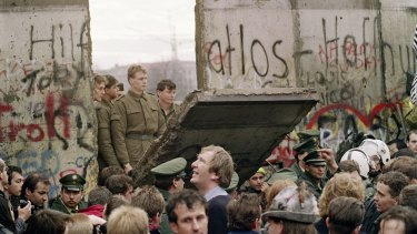 West Berliners watch East German border guards demolishing a section of the wall on November 11, 1989.