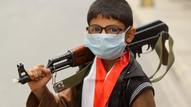Unrest continues: A young boy with a surgical mask and gun during a sandstorm in Sanaa on Friday.