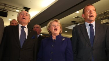 John Howard, Janette Howard and Tony Abbott sing the national anthem.