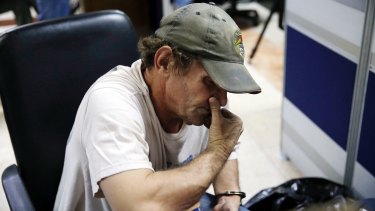 David Timothy Deakin is handcuffed to a chair at the National Bureau of Investigation in Manila, Philippines, on April 21.  Authorities say his arrest has resulted in one of the largest seizures of illicit digital content in the country's history.  