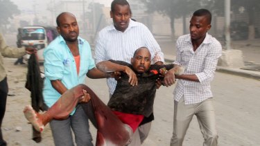 Somali men help a wounded civilian who was wounded in a suicide car bomb attack.