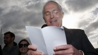 Prime Minister Malcolm Turnbull reads from a list of ALP spending pledges on Tuesday.