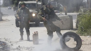 An Israeli soldier clears a burning tyre off the road during clashes with Palestinian demonstrators at the refugee camp of al-Arroub, near Hebron, in April. Sergeant Azaria told the court that soldiers in Hebron are on constant alert because of regular confrontations. 