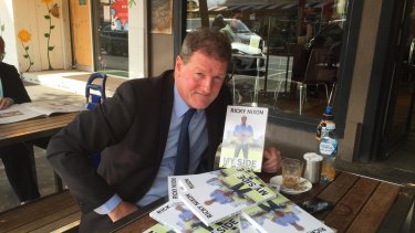 Ricky Nixon selling copies of his book outside a Port Melbourne bakery.