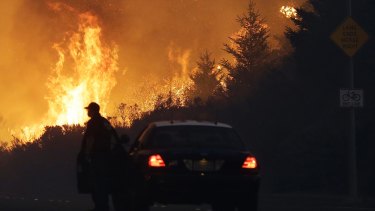 A law enforcement officer blocks a road as flames burn in a residential area in Santa Rosa, California.