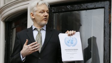 Julian Assange, pictured on the balcony of Ecuador's London embassy, holds the UN report that says he is being 'arbitrarily detained' by Britain and Sweden.