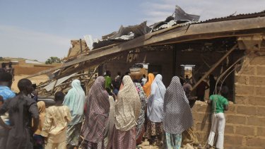 People gather around the Redeemed Christian Church of God, after a woman suicide bomber killed five people in Potiskum, Nigeria. It was the first in a string of attacks on Sunday that killed 44.