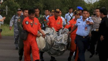 Rescue workers carry debris recovered from the ocean, presumed to be part of the AirAsia plane.