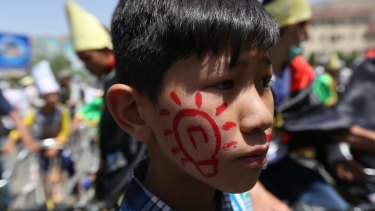 A young Hazara wears a symbol of electricity as thousands of demonstrators march towards the centre of Kabul, Afghanistan.