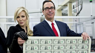 US Treasury Secretary Steven Mnuchin and his wife Louise Linton hold a sheet of $1 notes bearing Mnuchin's name.