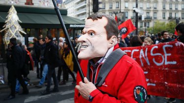 A man wearing a mask of of French President Emmanuel Macron attends a demonstration in Paris this month.