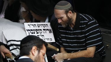 A mourner sits beside the body of Aryeh Kopinsky, one of the five victims of the Har Nof synagogue attack, during his funeral in Jerusalem on November 18.