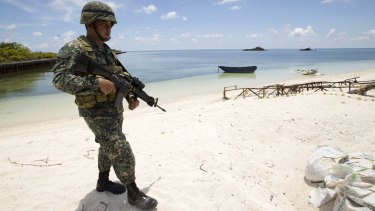 A Filipino soldier patrols the shore of Pag-asa Island in the Spratly chain on Monday.