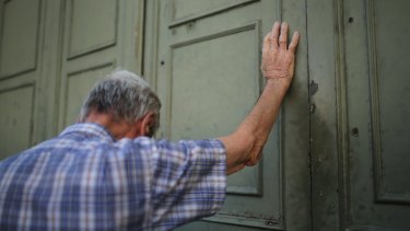 A despairing Greek citizen leans against the closed door of a bank in Athens.