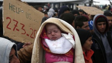 A migrant holds a baby during a protest demanding the opening of the border between Greece and Macedonia on Sunday. 