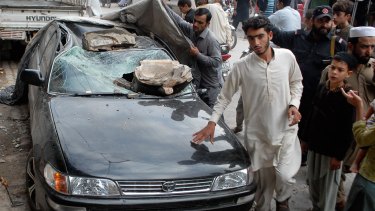People stand near a car in Peshawar, Pakistan, after Monday's earthquake.