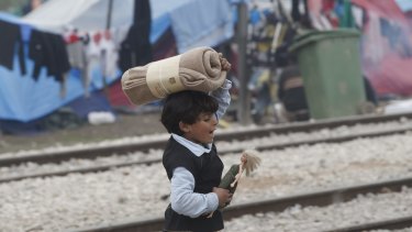 A child of a migrant family walks holding a doll in the makeshift refugee camp at the northern Greek border point of Idomeni, Greece, on Thursday.