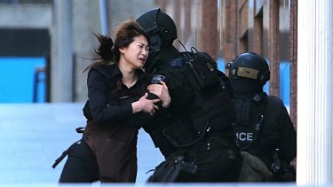 One of the women held hostage inside the cafe for several hours runs into the arms of police after being freed. 