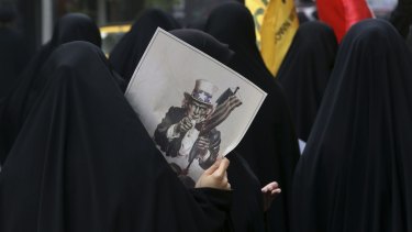 A female Iranian demonstrator with a caricature of Uncle Sam at an anti-US rally in Tehran last month. 