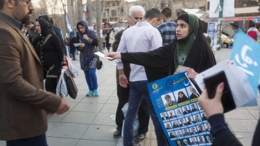 A woman distributes election posters in downtown Tehran.