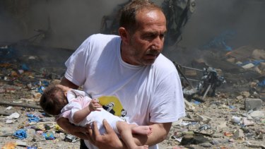 A man holds a baby that survived what activists said was a site in Aleppo hit by a barrel bomb dropped by forces loyal to Syrian President Bashar al-Assad in June. 