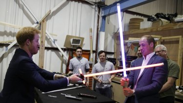 Prince Harry (left) and Prince William try out lightsabers during a tour of the <i>Star Wars</i> sets at Pinewood studios.