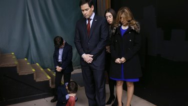 Marco Rubio and his family pray during the opening of a caucus site.