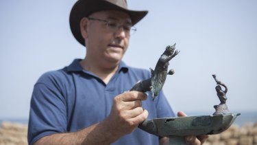 Jacob Sharvit, director of the Marine Archaeology Unit of the Israel Antiquities Authority, holds a bronze lamp depicting the image of a Roman sun god Sol Invictus, in Cesarea, Israel.
